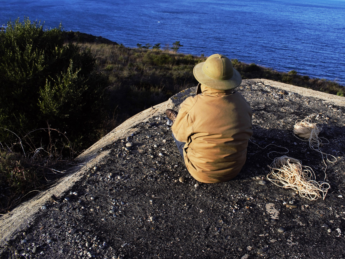 man sitting on the cliff looking at the sea