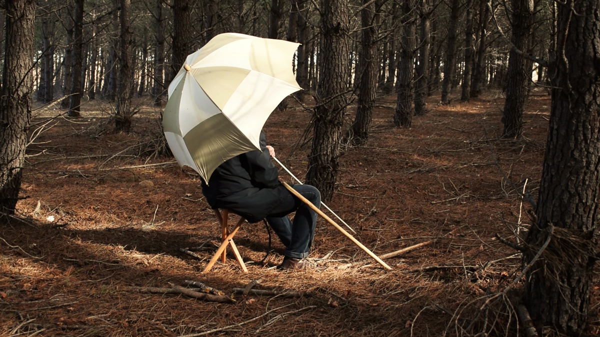 man holding an umbrella in the middle of forest